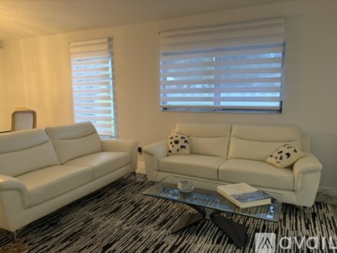 A living room with two white couches and a coffee table.