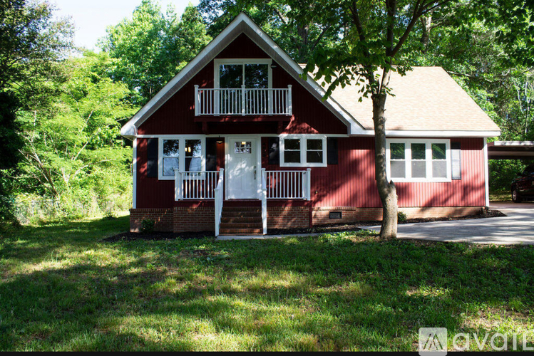 A red house with a balcony and a tree in front.