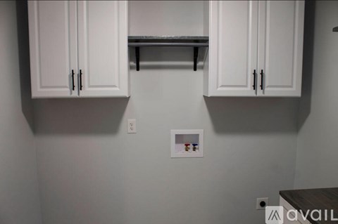A kitchen with white cabinets and a small shelf with spices.