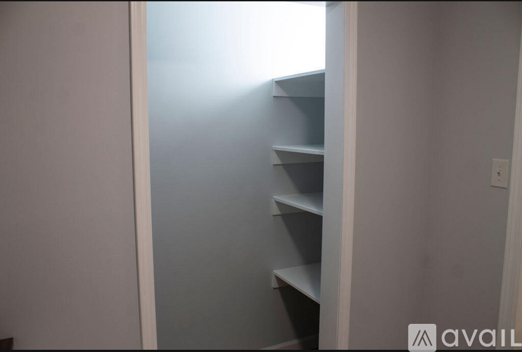 Empty shelves in a room with light shining through a door.