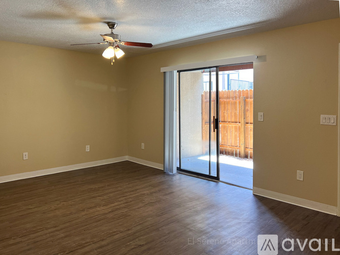 A room with a ceiling fan and sliding glass doors leading to a backyard.