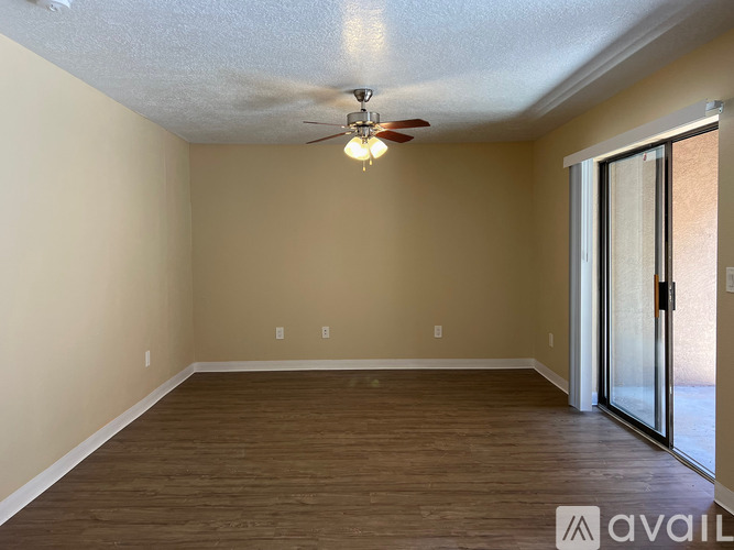 A room with a ceiling fan and sliding glass door.