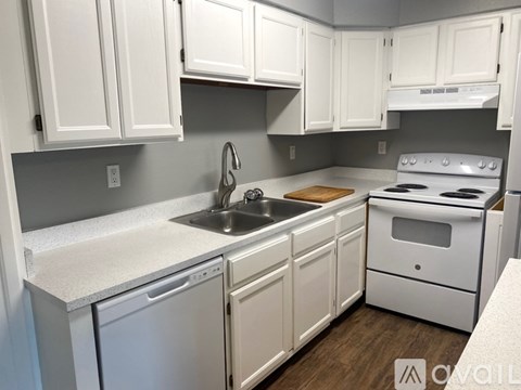 A kitchen with white cabinets and a white stove top oven.