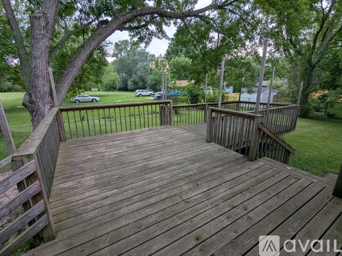 A wooden deck with railings and steps leading to a grassy area.