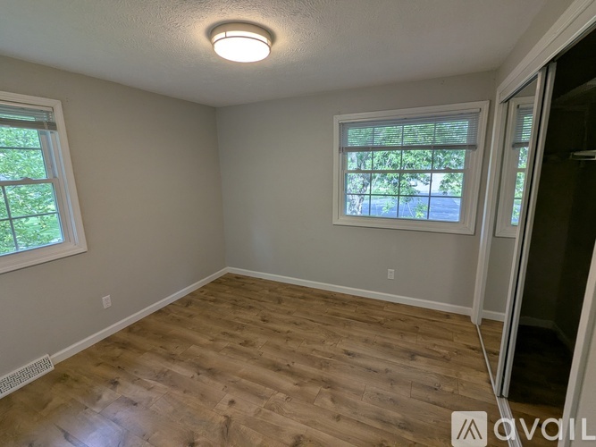 A room with wooden flooring and a window with blinds.