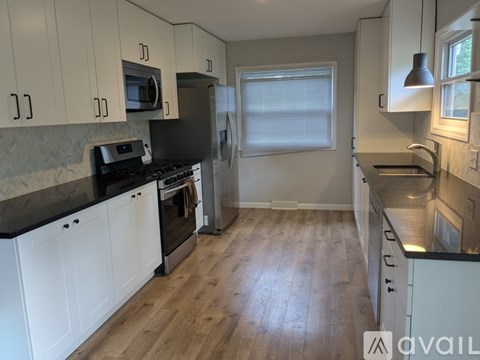 A kitchen with white cabinets and black countertops.