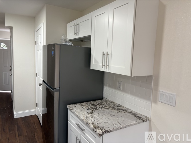 A kitchen with a black fridge and white cabinets.