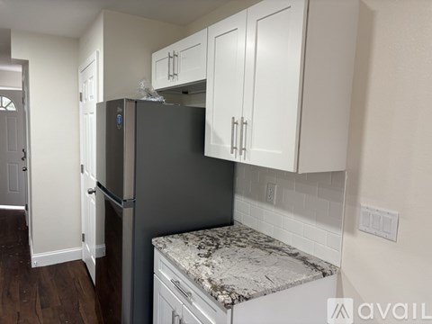 A kitchen with a black fridge and white cabinets.