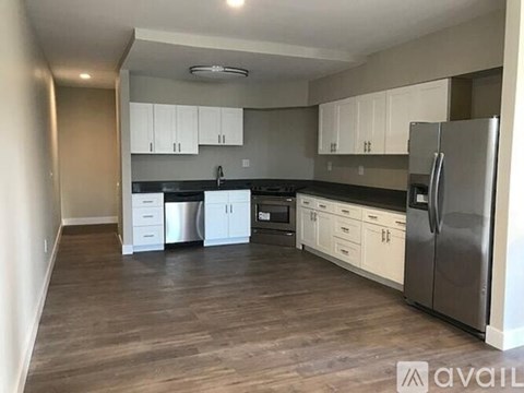 A kitchen with white cabinets and a stainless steel refrigerator.