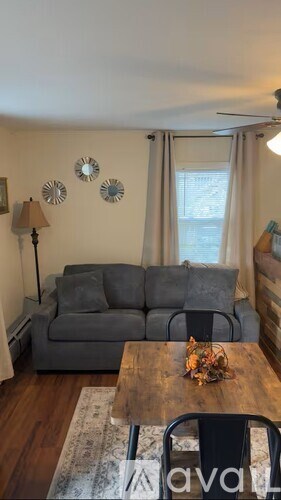 A grey couch sits in a living room with a wooden table in front of it.
