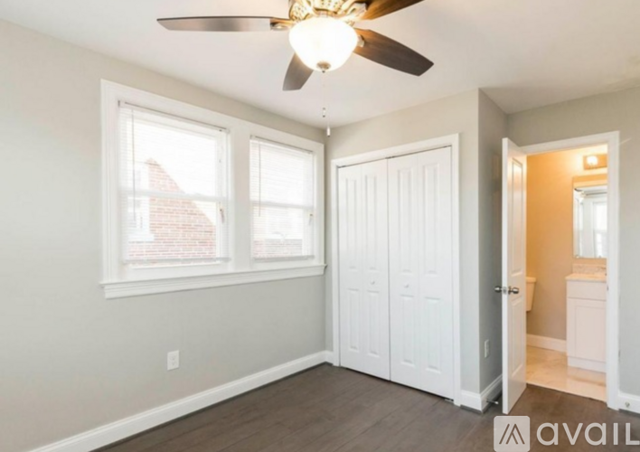 A room with a ceiling fan and a window overlooking a brick building.