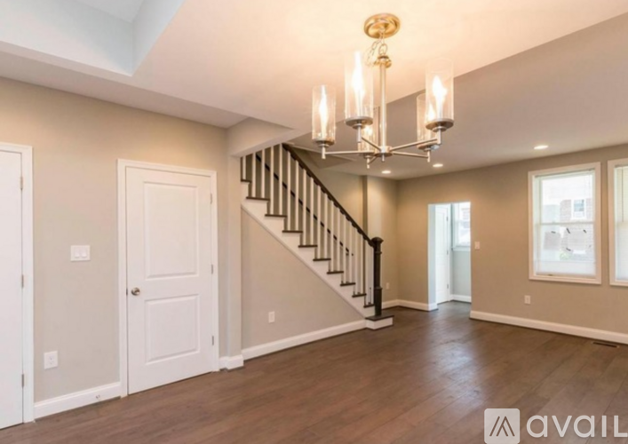 A spacious room with a staircase and a chandelier.