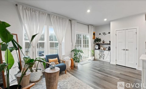 A living room with a blue chair and a large window with white curtains.