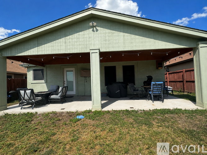 A house with a covered patio and lawn chairs.
