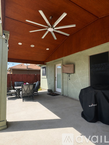 A patio with a ceiling fan and a covered table.