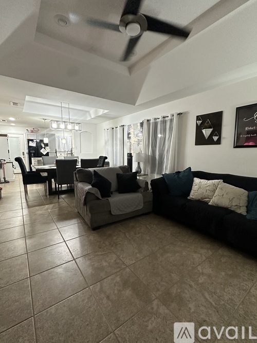 A living room with a black couch and a dining table.