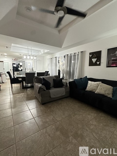 A living room with a black couch and a dining table.