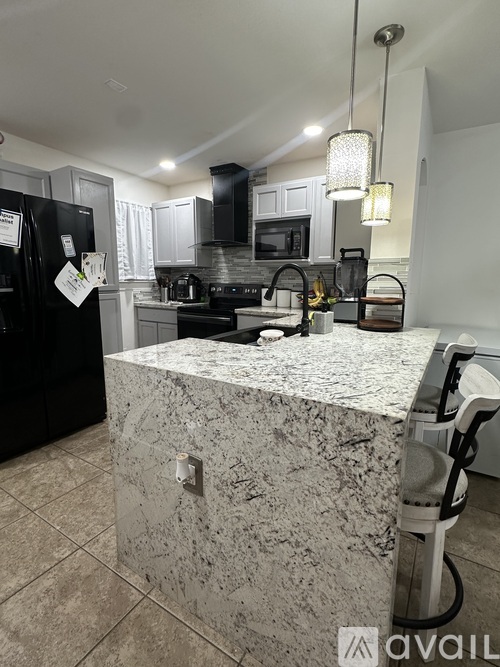 A kitchen with a granite countertop and a black refrigerator.