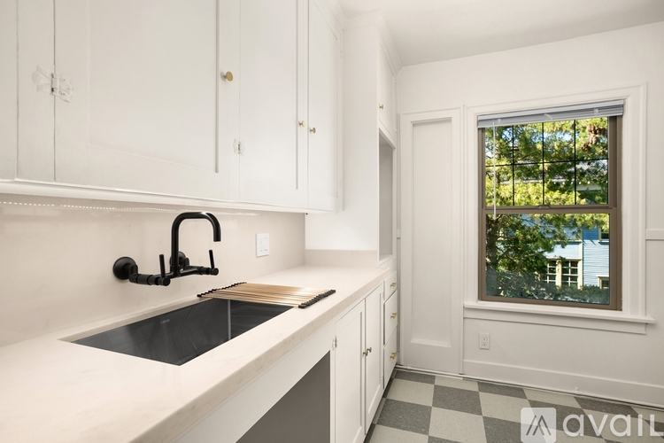 A kitchen with white cabinets and a black faucet.