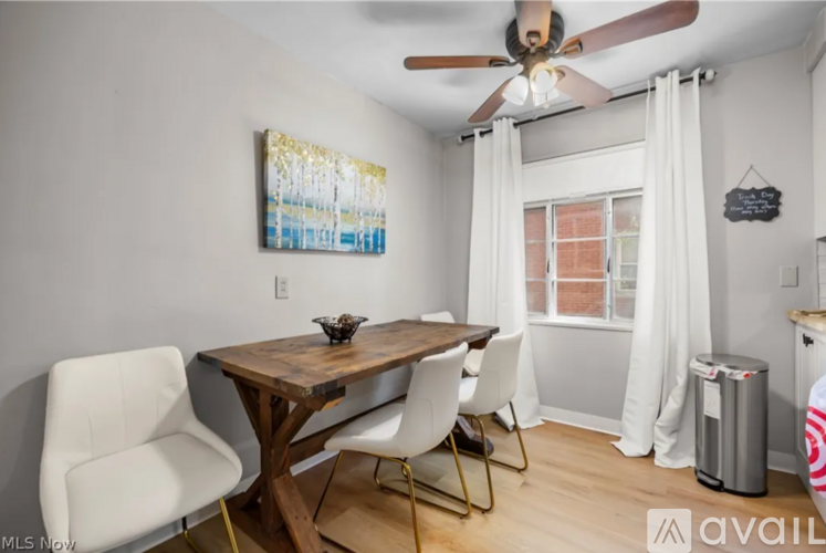 A dining room with a wooden table and white chairs.