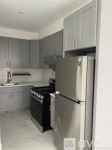 A kitchen with a black stove top oven and a white refrigerator.