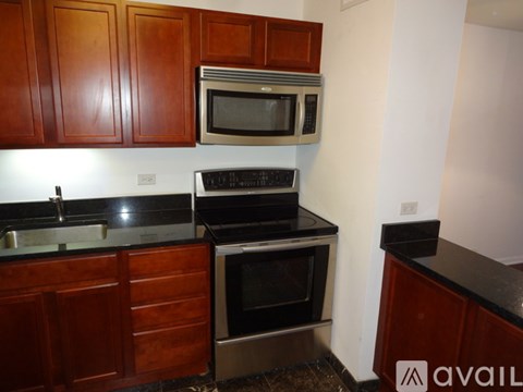 A kitchen with wooden cabinets and black countertops.