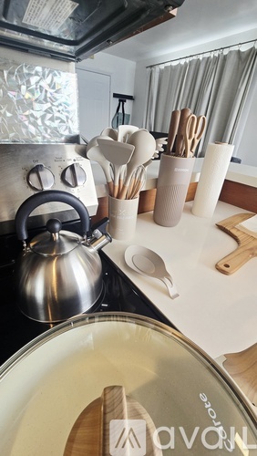 A kitchen counter with a kettle, a pot, and utensils.