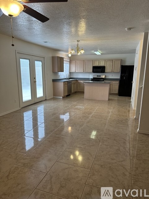 A kitchen with a black refrigerator and a ceiling fan.