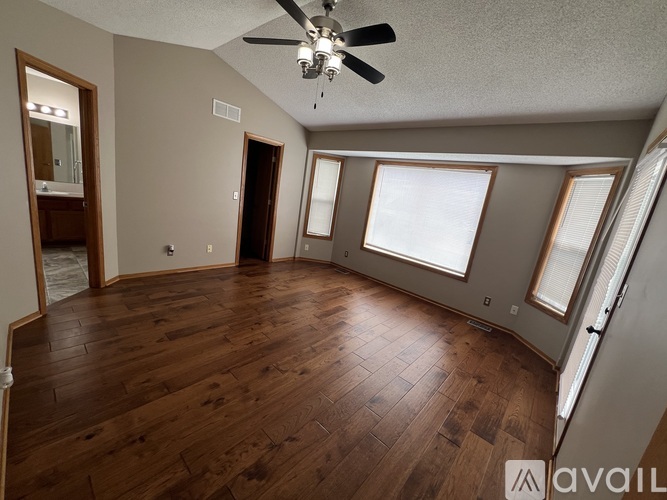 A spacious room with wooden floors and a ceiling fan.