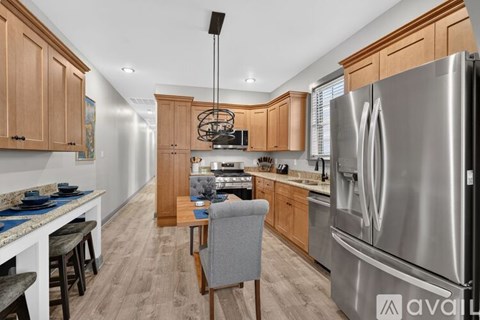 A kitchen with a large refrigerator and a dining table with chairs.
