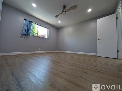 A room with a ceiling fan and a window with blue curtains.