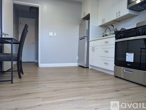 A kitchen with a black chair and a black microwave.