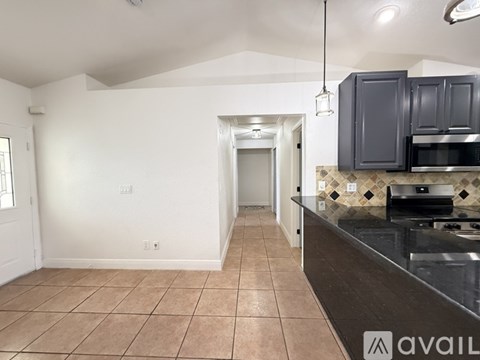 A kitchen with a black counter top and white walls.