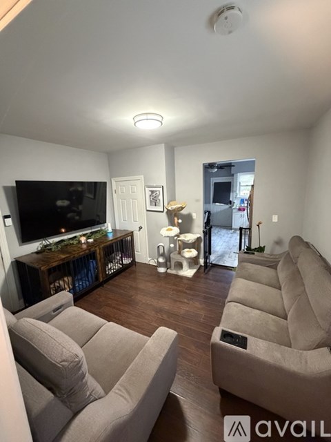 A living room with a television, two couches, and a fireplace.