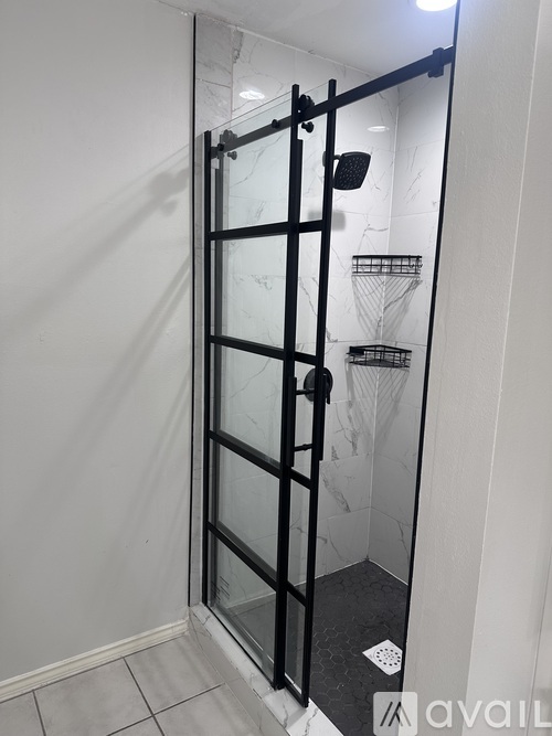 A black shower stall with a glass door and a black handle.
