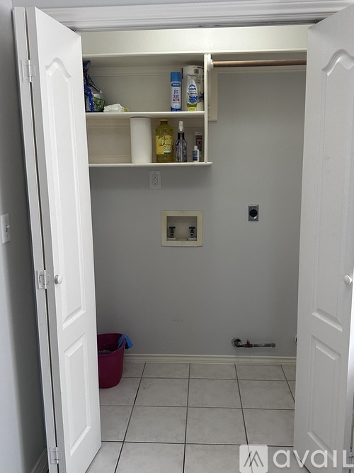 A white door is open to a small pantry with a few items on the shelves.