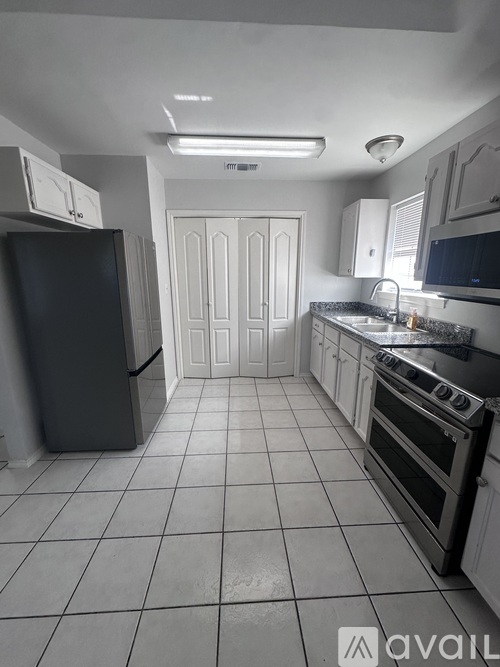 A kitchen with white cabinets and a black refrigerator.