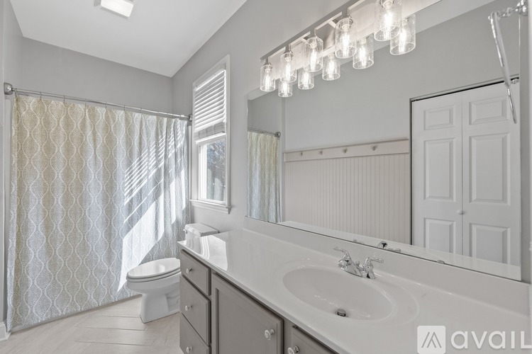 A bathroom with a white sink, toilet, and shower curtain.