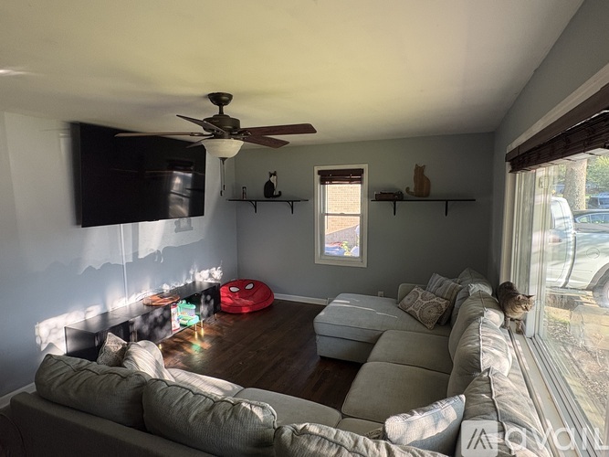 A living room with a grey couch and a red bean bag.
