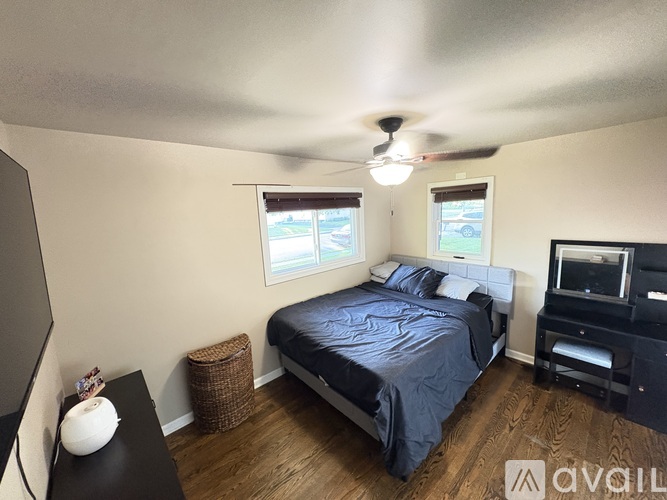 A bedroom with a bed, a ceiling fan, and a television.