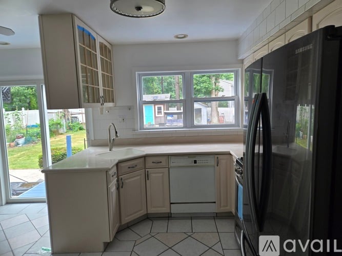 A kitchen with a black fridge and white cabinets.