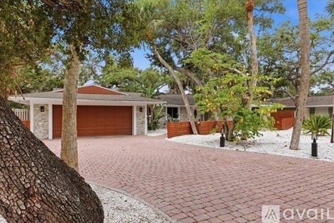 A house with a red roof and a driveway in front of it.