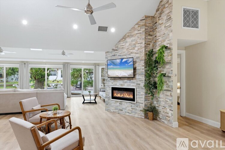 A living room with a stone fireplace and a flat screen TV mounted above it.