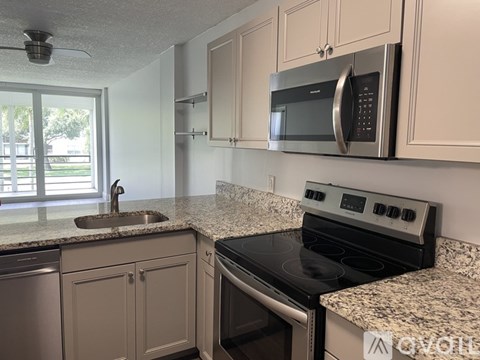A kitchen with a black stove top oven and a silver microwave above it.