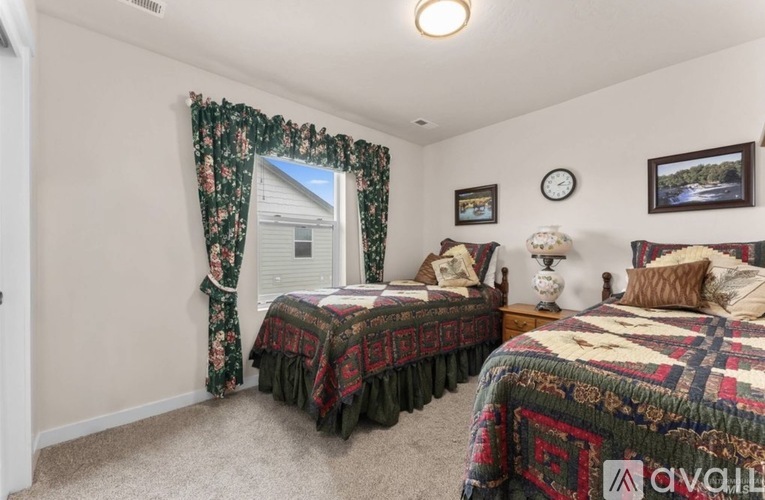 A bedroom with two beds and a window with curtains.