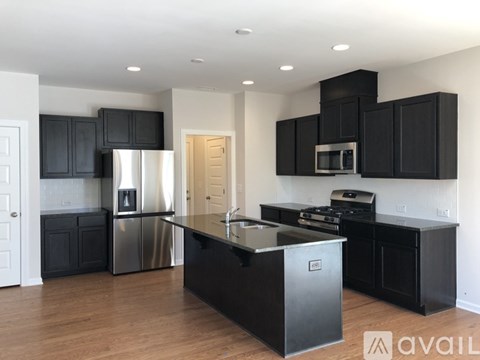 A modern kitchen with black cabinets and stainless steel appliances.