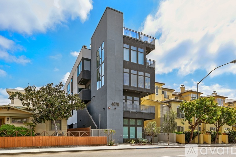A modern building with a grey facade and large windows is the main focus of the image.