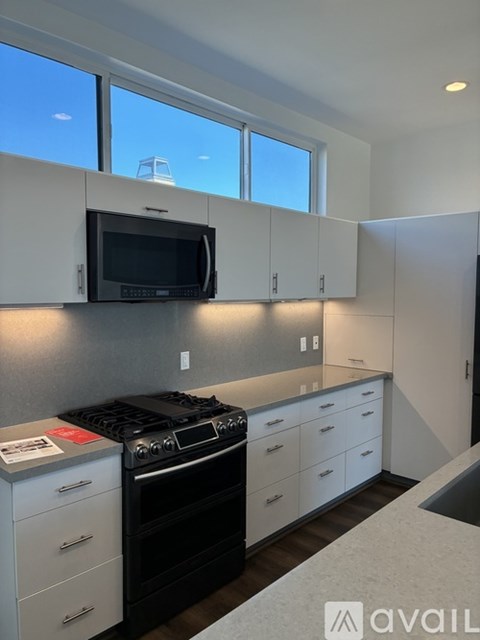 A kitchen with white cabinets and a black microwave.
