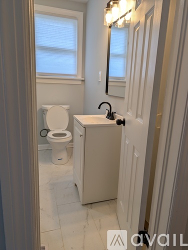 A bathroom with a toilet, sink, and mirror.