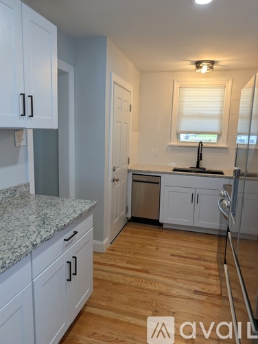 A kitchen with white cabinets and a granite countertop.